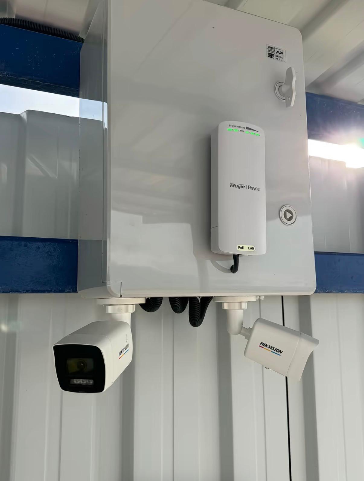 Cutie de exterior cu punte radio Ruijie Reyee și două camere Hikvision montate dedesubt, în județul Sibiu