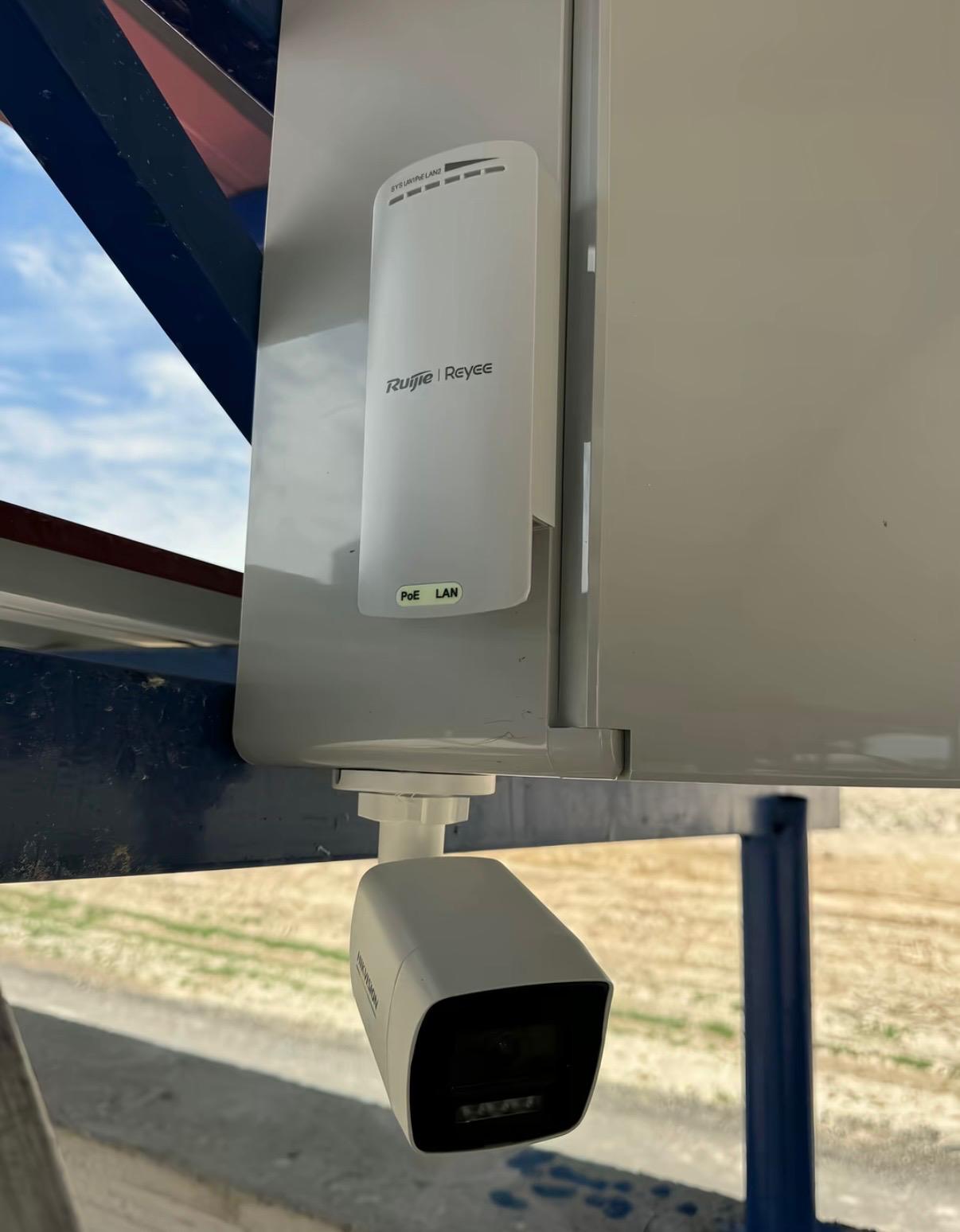 Punte radio Ruijie Reyee și cameră Hikvision montate pe cutie de exterior pe structura metalică a unei hale în județul Sibiu