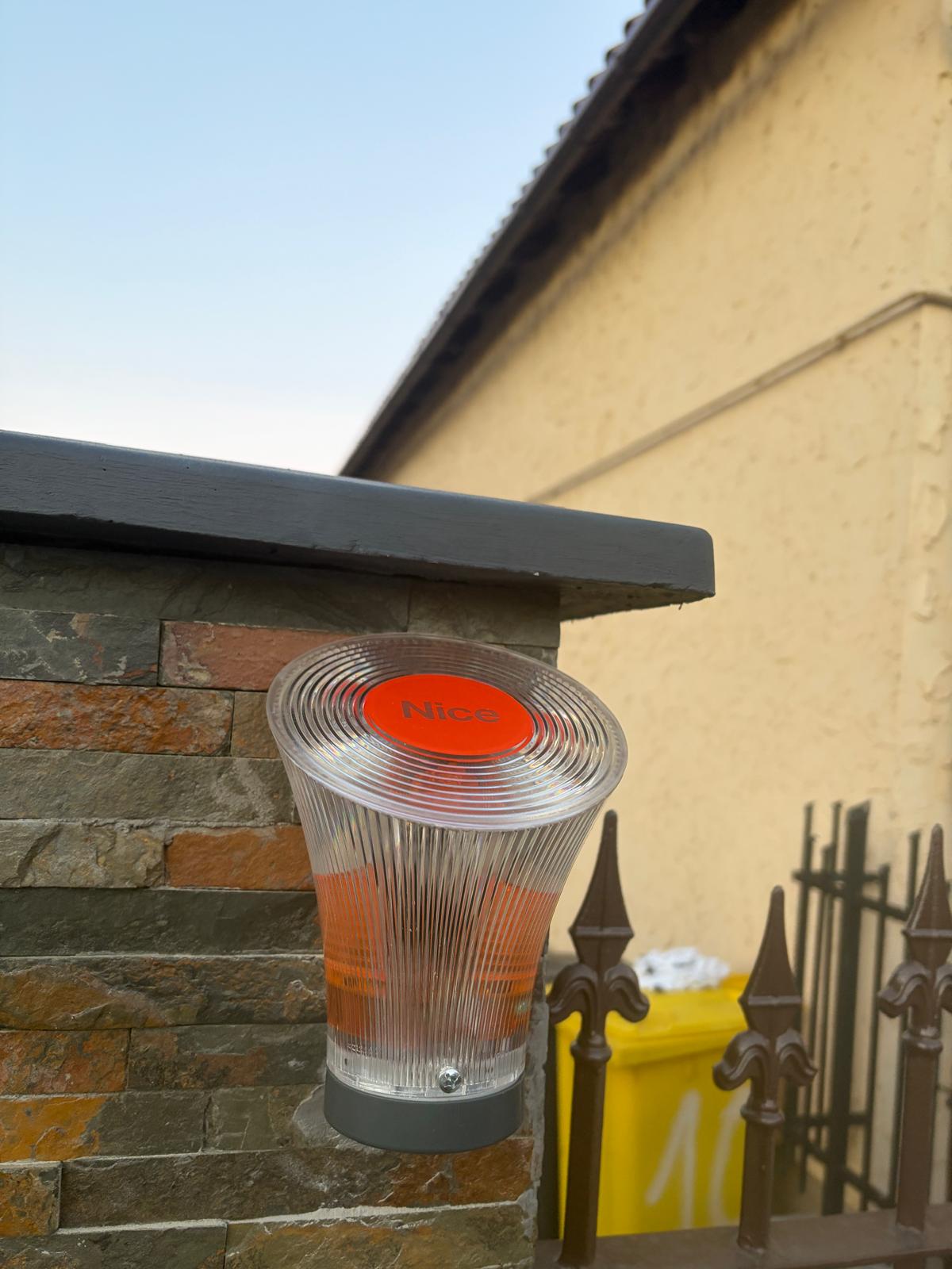 Lampa de semnalizare Nice montată pe stâlpul porții automatizate în Sibiu